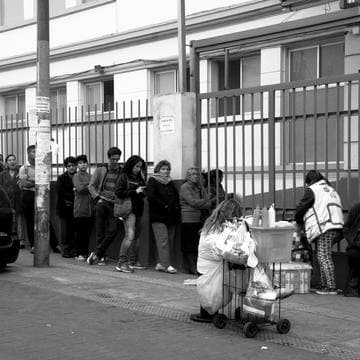 Grupo de personas reunidas frente a un mercado, blanco y negro