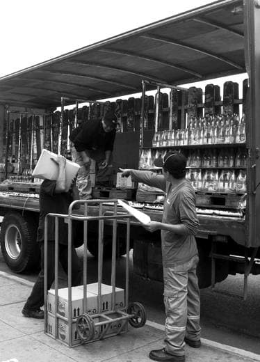 Trabajador cargando mercadería en la calle, blanco y negro